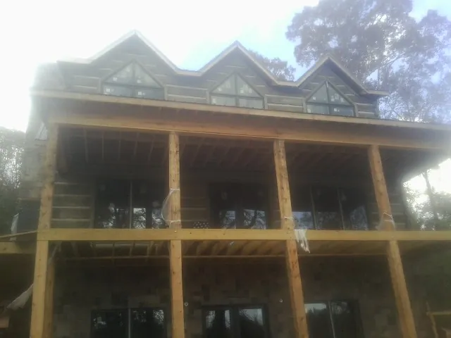 Dormers and porch framing on a large log home under construction — Roof Coating work by our crew in Lafitte