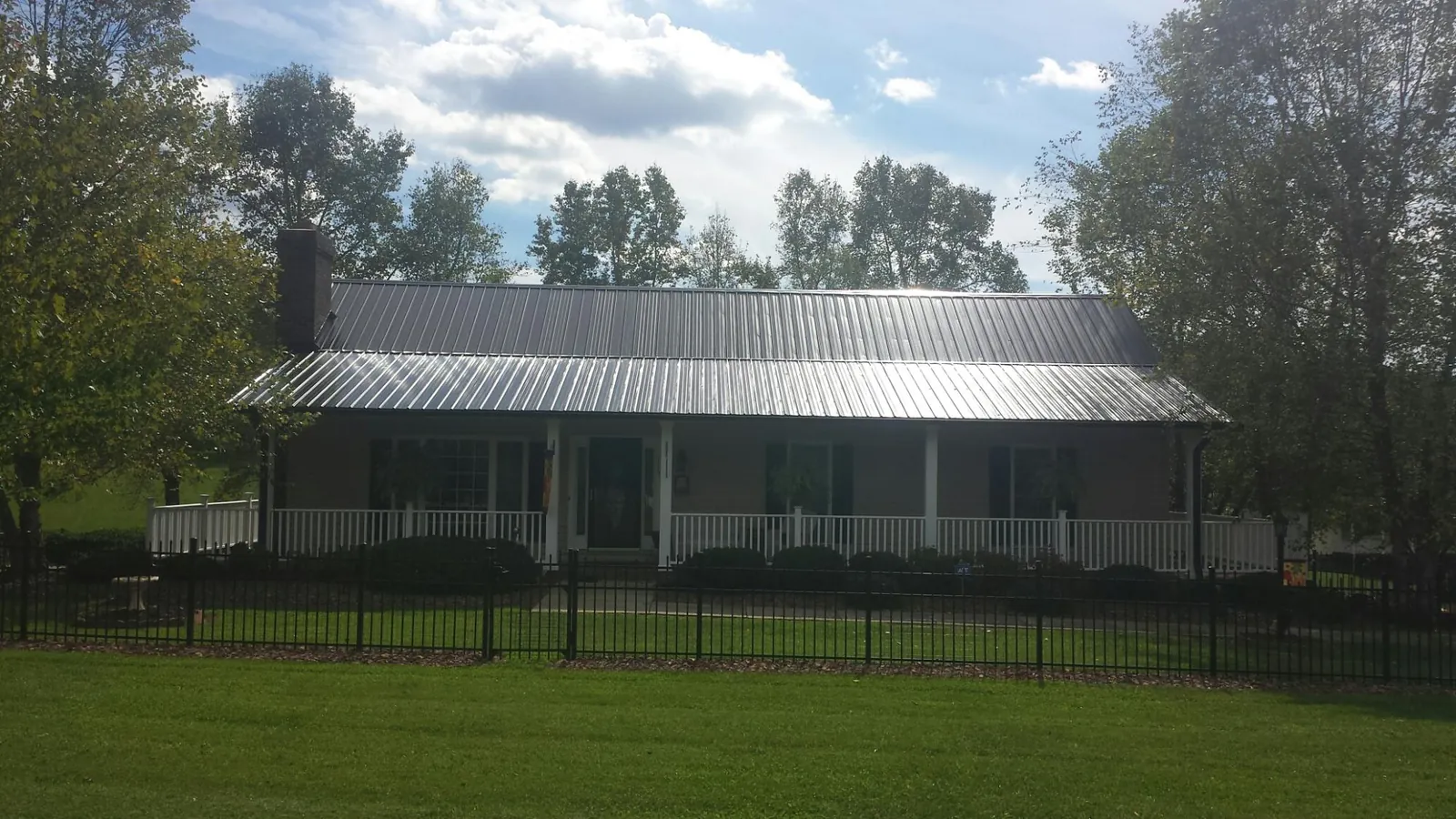 Gray metal roof on a brick ranch with a full width front porch — Gutter Guard Installation work by our crew in Lafitte